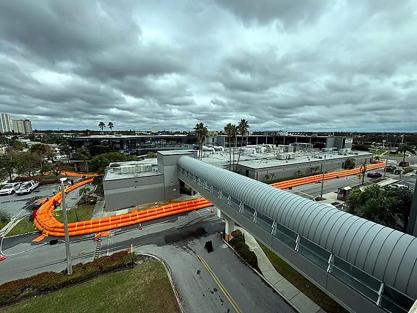 Water-filled barrier line running alongside a hospital skybridge and clinical building