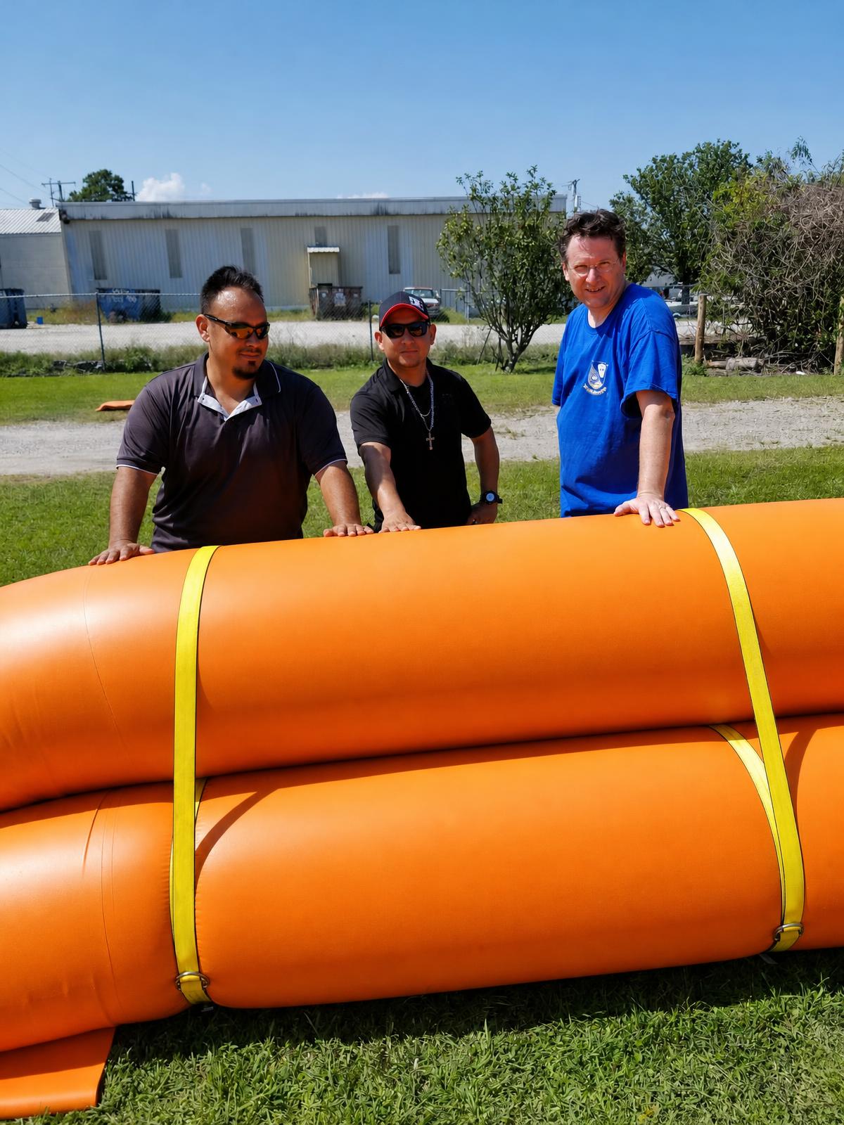 Three Texas Flood Fighters crew members standing behind a double-stacked water-filled barrier
