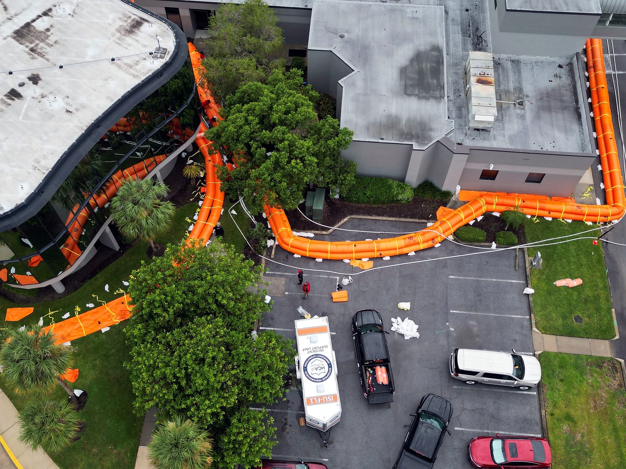 Aerial view of an orange water-filled barrier line wrapped around a Florida hospital campus and parking area