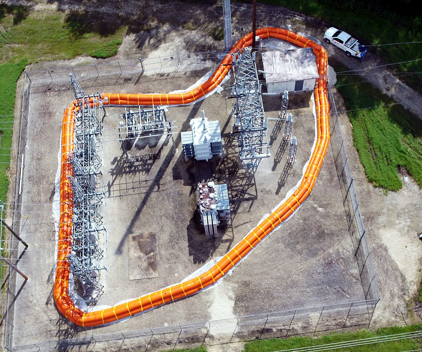 Aerial view of a water-filled barrier ring enclosing an electrical substation